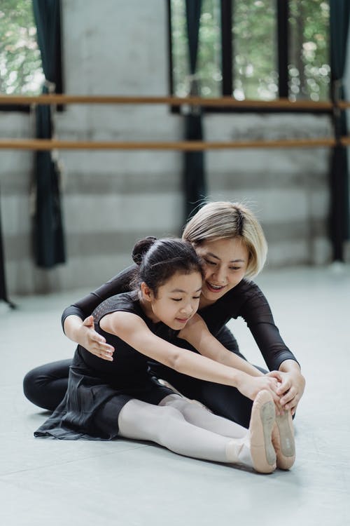 亚洲女芭蕾舞教练帮助芭蕾舞女孩伸展身体 · 免费素材图片