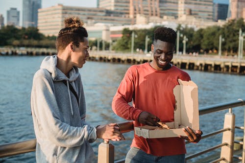 快乐的多种族的男人，在城市的海滨上享受美味的比萨 · 免费素材图片