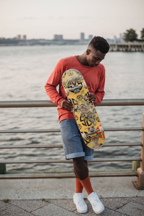 滑板站在海滨的黑人男子 · 免费素材图片