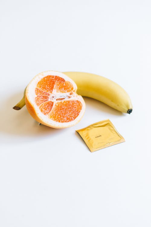 香蕉和橙色水果旁边的避孕套 · 免费素材图片