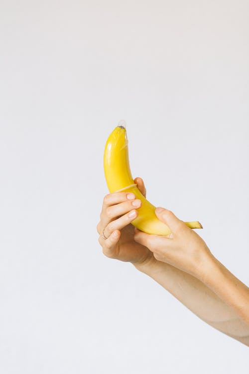 在香蕉上包裹避孕套的人 · 免费素材图片