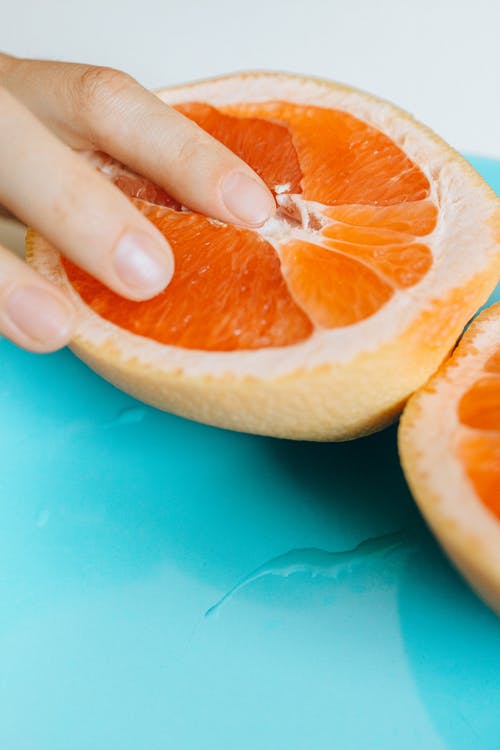 人接触切成薄片的橙色水果 · 免费素材图片