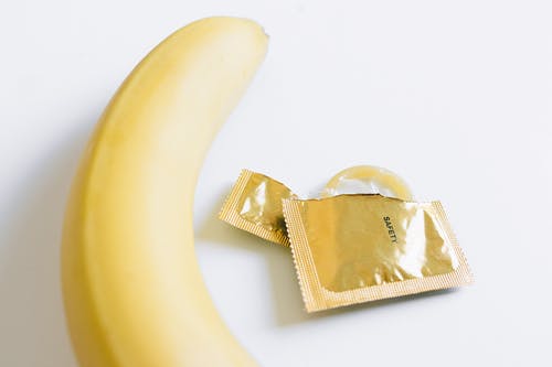 香蕉旁边的解开的避孕套 · 免费素材图片