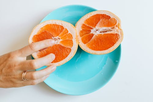 人接触切成薄片的橙色水果 · 免费素材图片