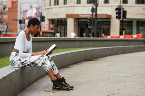 在城市街道上的殷勤黑人妇女阅读书 · 免费素材图片