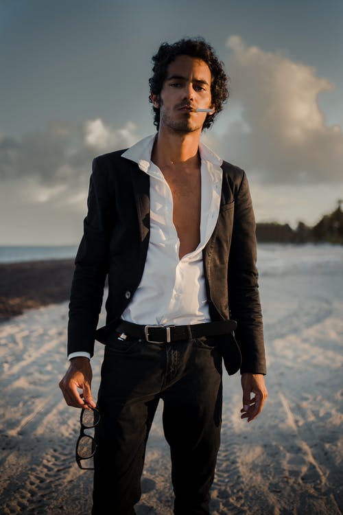 打开衬衫和吸烟站在海滩上的男人 · 免费素材图片