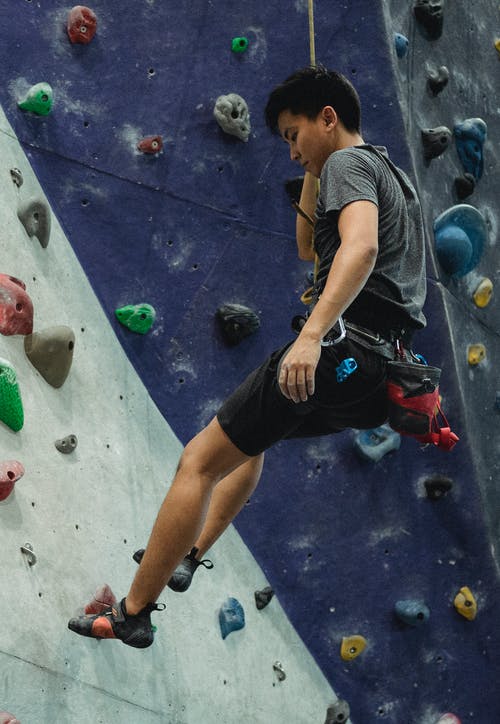 亚洲男性登山者在训练期间提升人造岩石 · 免费素材图片