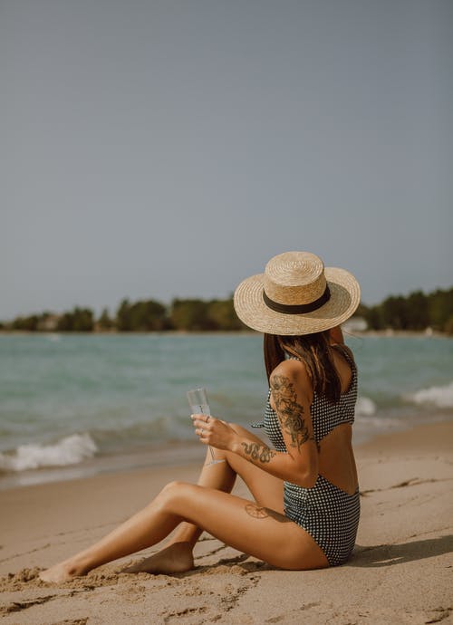 坐在沙滩上的泳装轻松的女人 · 免费素材图片