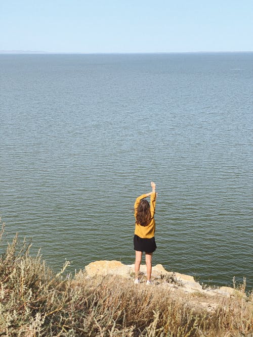 匿名的女士，从岩石峭壁享受海景 · 免费素材图片