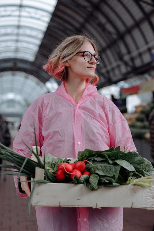 拿着绿色蔬菜的桃红色礼服衬衣的妇女 · 免费素材图片