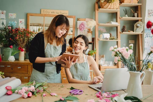 积极多种族妇女在花卉商店使用平板电脑 · 免费素材图片
