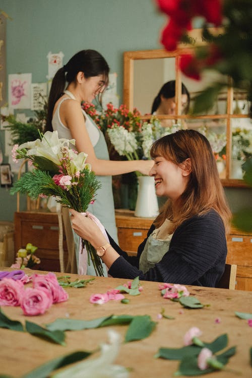性格开朗的同事在店里制作鲜花花束 · 免费素材图片