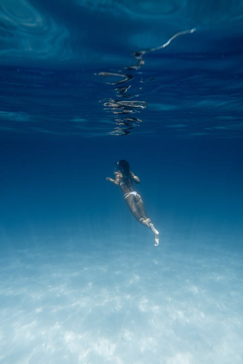 在夏天在蓝色的大海中潜水的匿名女人 · 免费素材图片