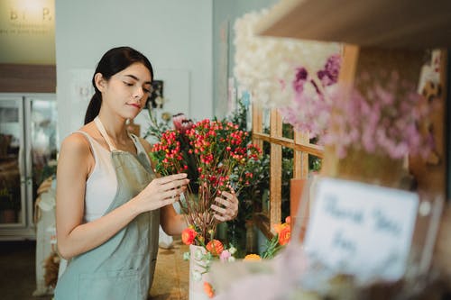 美满的女人在商店安排花束 · 免费素材图片