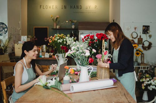 幸福的女人，用鲜花和笔记本电脑工作 · 免费素材图片