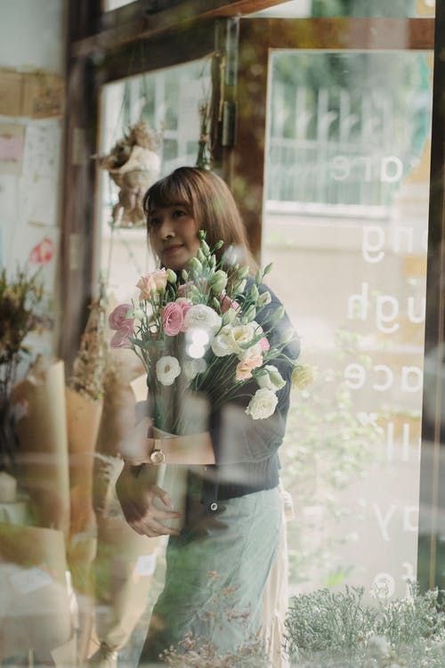 束鲜花走进商店的族裔女人 · 免费素材图片