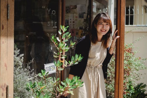 站立在商店门道入口的围裙的微笑的亚裔妇女 · 免费素材图片