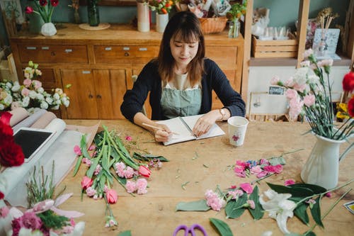 亚洲花店在笔记本上记笔记 · 免费素材图片