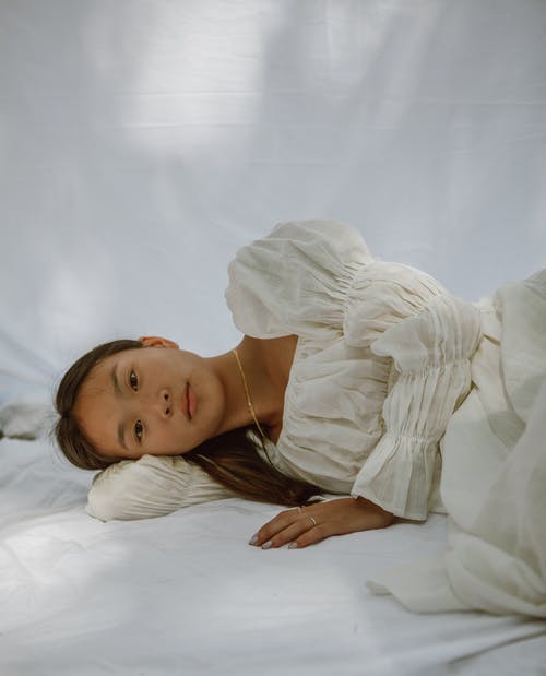宁静的年轻亚洲女性，早上躺在白色的毯子上 · 免费素材图片
