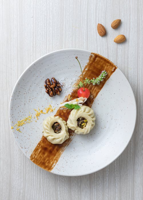 在白色陶瓷板上切成薄片的白奶油面包和绿叶 · 免费素材图片