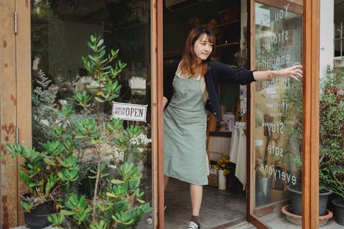 坦然的女人站在商店的门口 · 免费素材图片