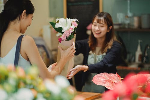 快乐的亚洲花店卖花束给女性顾客 · 免费素材图片
