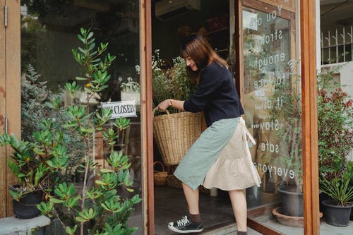 女人提着篮子进入花店 · 免费素材图片