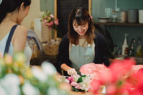 微笑亚洲花店为女性客户安排花束 · 免费素材图片