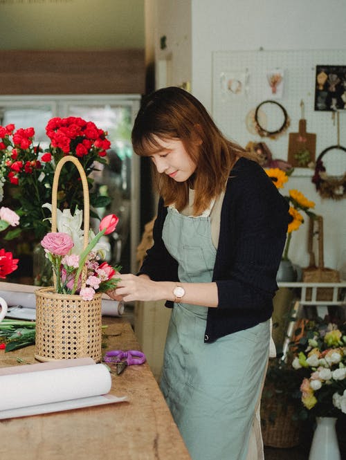 在篮子里制作花束的积极亚洲花店 · 免费素材图片