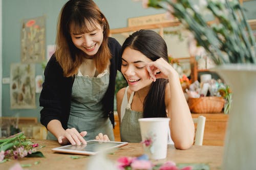 浏览在花店的片剂的快乐的不同种族的女性卖花人 · 免费素材图片