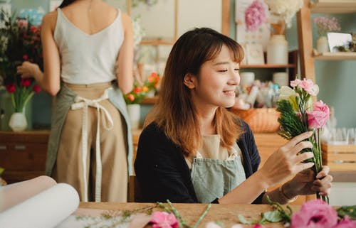 性格开朗的亚洲花店鲜花店里安排花束 · 免费素材图片