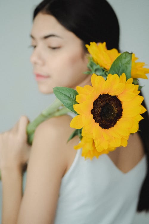 播种少妇站立用在肩膀的黄色向日葵 · 免费素材图片