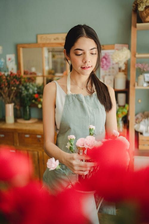 围裙的花店在舒适的商店里制作花束 · 免费素材图片