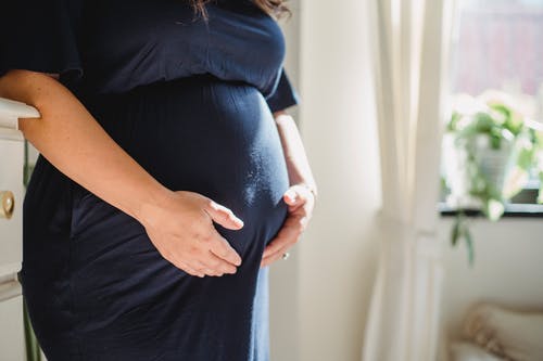 不露面的孕妇拥抱腹部在房子里 · 免费素材图片