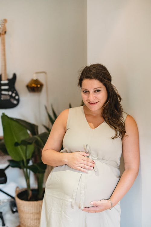 怀孕的女性感人的肚子在房间里 · 免费素材图片