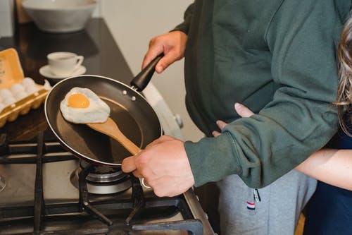 在家里的厨房里的人准备在锅里煎的鸡蛋 · 免费素材图片