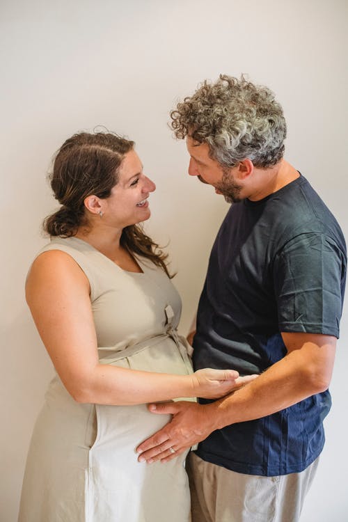 拥抱与白色背景的丈夫的正面孕妇 · 免费素材图片