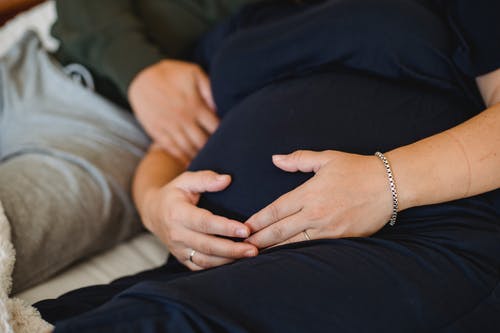 匿名的孕妇爱抚肚子附近丈夫在床上 · 免费素材图片