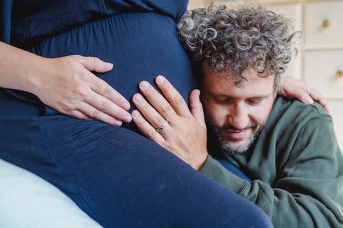 蓬头垢面的男人拥抱农作物孕妇的肚子在房子里 · 免费素材图片