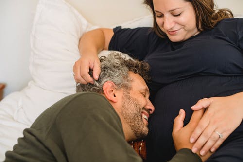性格开朗的人爱抚作物怀孕的妻子在床上的肚子 · 免费素材图片