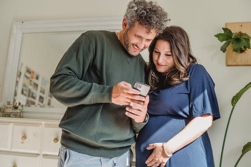有怀孕的妻子在家看智能手机的成年男子 · 免费素材图片