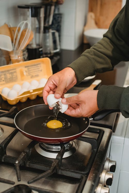 男人在厨房里把鸡蛋分成锅 · 免费素材图片