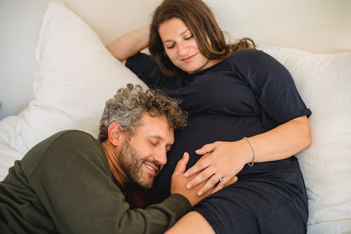 梦幻般的男人在床上爱抚作物怀孕妻子的肚子 · 免费素材图片
