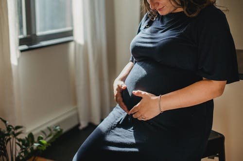 在阳光下在家平静怀孕的女性抚摸肚皮 · 免费素材图片