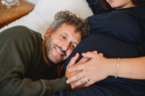 饱满的男人在床上抚摸着无法识别的孕妇的肚子 · 免费素材图片