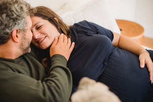 作物人在房子的床上抚摸怀孕的妻子 · 免费素材图片