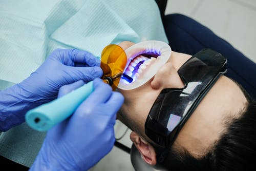 牙医用紫外线设备对病人进行口腔检查 · 免费素材图片