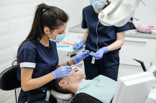女牙医助理治愈病人的牙齿 · 免费素材图片