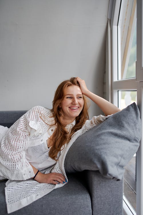 靠窗的舒适沙发上休息的幸福女人 · 免费素材图片