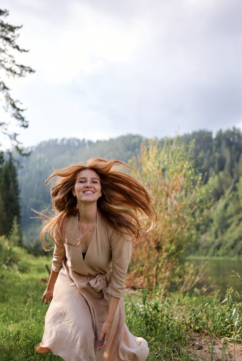 在河海岸上飞舞的头发的幸福女人 · 免费素材图片